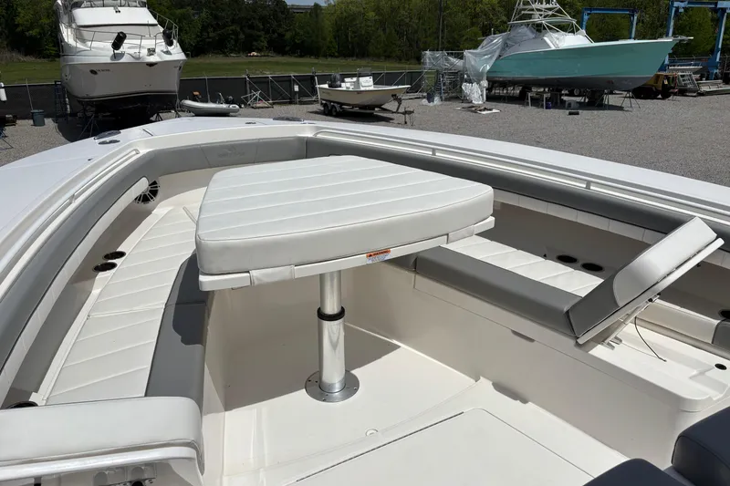 Slide: The Image of 2023 Regulator 41 boat interior with cushioned seating and table in a marina setting. - 19