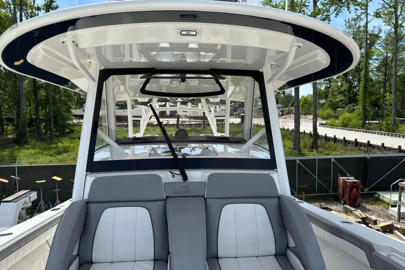 Slide: The Image of 2023 Regulator 41 boat interior with seating and helm, surrounded by greenery. - 29