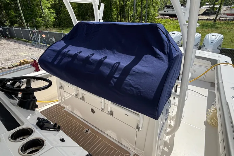 Slide: The Image of 2023 Regulator 41 boat helm with blue cover, featuring steering wheel and cup holders. - 66