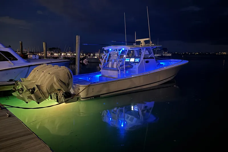 Slide: The Image of 2023 Regulator 41 boat illuminated at night with blue and green lights in a marina. - 77