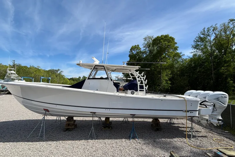 Slide: The Image of 2023 Regulator 41 boat on stands, white hull, triple outboard engines, clear sky background. - 9