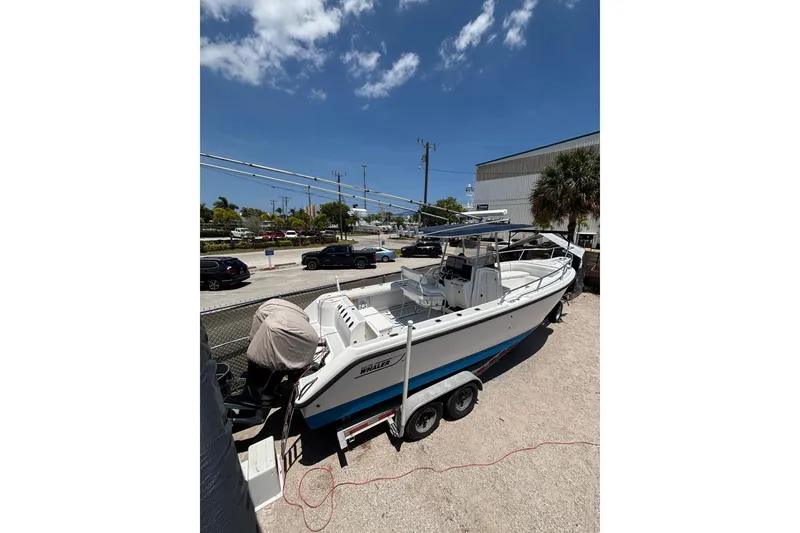 The Image of 2001 Boston Whaler 26 Outrage boat on trailer under clear blue sky. - 2