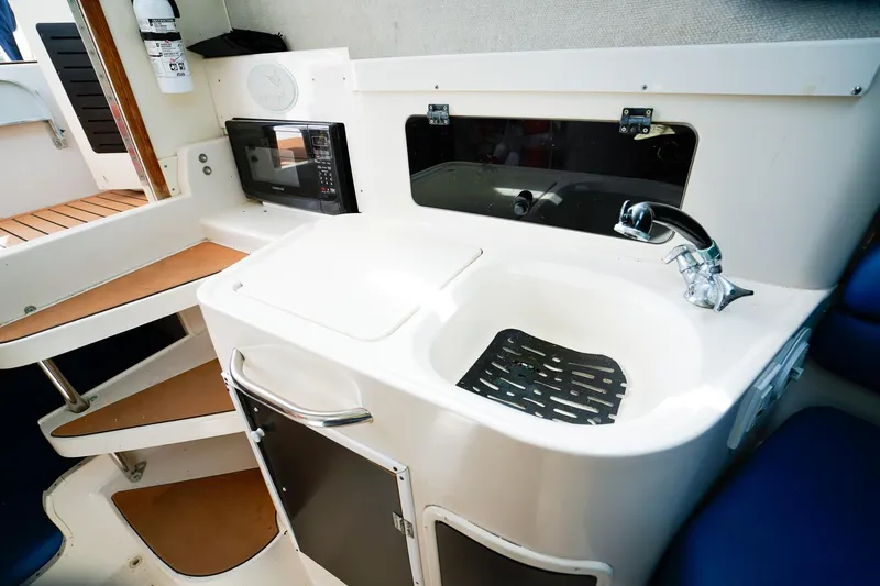 Slide: The Image of 1995 Grady-White Marlin 300 boat interior with kitchenette, featuring sink and microwave. - 16