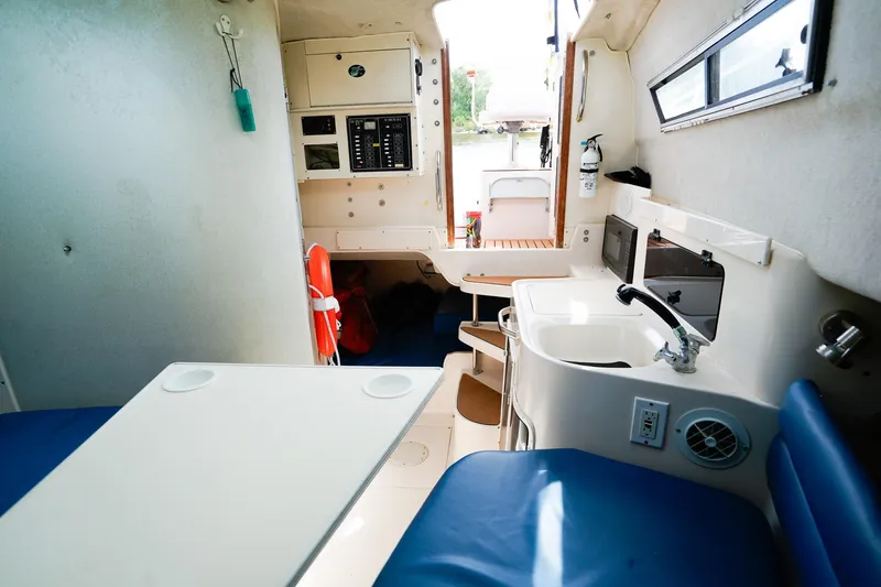 Slide: The Image of Interior of a 1995 Grady-White Marlin 300 boat, featuring a compact kitchen and seating area. - 21