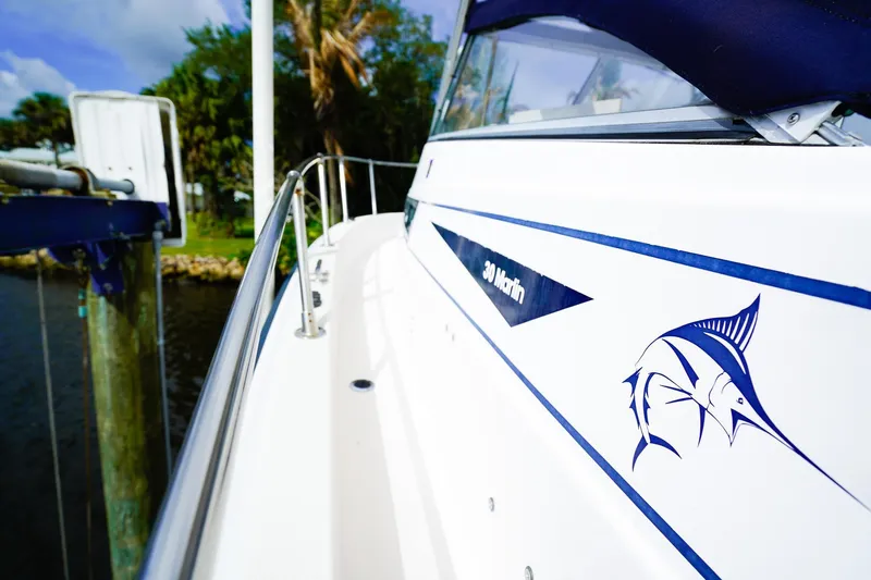 Slide: The Image of 1995 Grady-White Marlin 300 boat with marlin graphic, docked near lush greenery. - 22