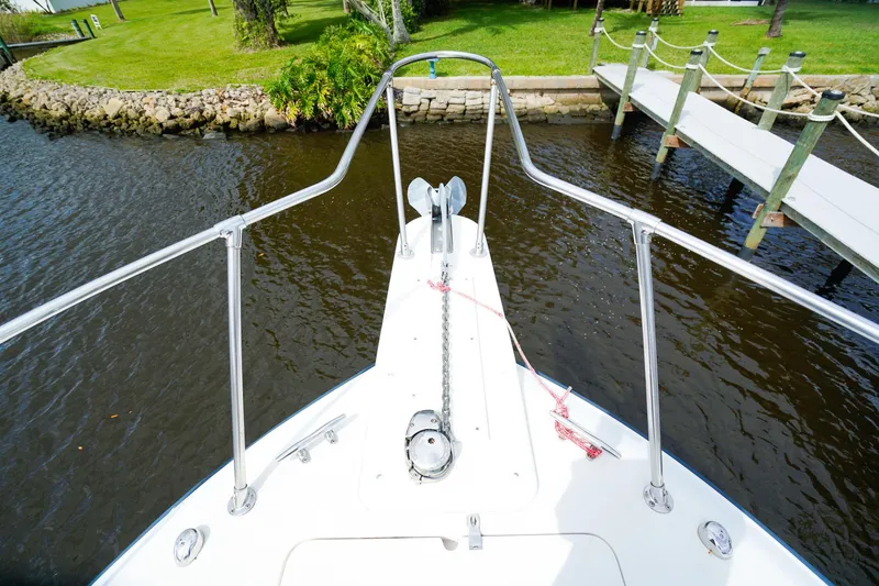 Slide: The Image of Bow view of 1995 Grady-White Marlin 300 boat docked by a grassy shoreline. - 24