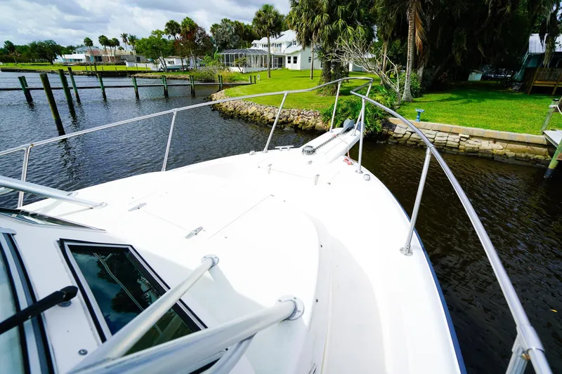 Slide: The Image of Bow view of 1995 Grady-White Marlin 300 boat docked by lush waterfront. - 26