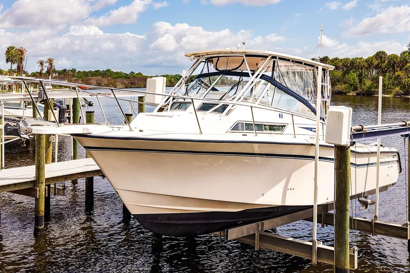 Slide: The Image of 1995 Grady-White Marlin 300 boat docked on a lift by the water. - 27