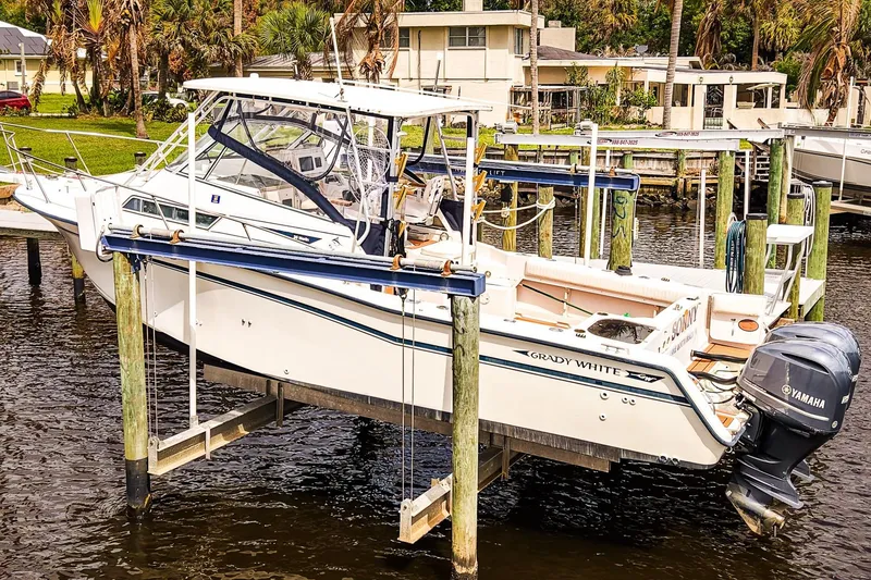 Slide: The Image of 1995 Grady-White Marlin 300 boat on lift, docked by waterfront homes. - 28