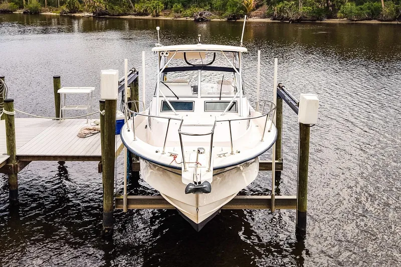 Slide: The Image of 1995 Grady-White Marlin 300 boat docked on a lift by a serene river. - 29