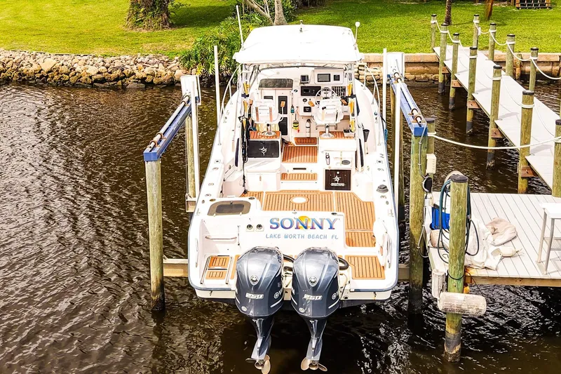 Slide: The Image of 1995 Grady-White Marlin 300 boat docked, featuring twin engines and wooden deck. - 30