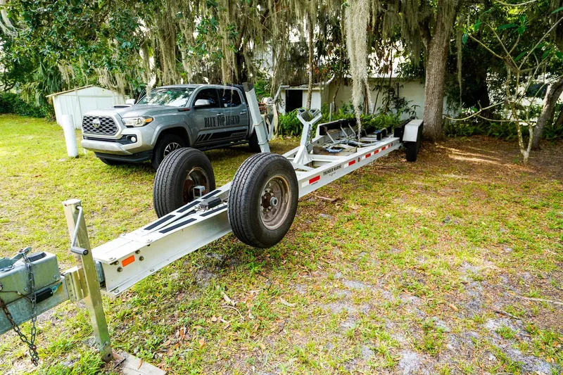 Slide: The Image of Trailer for 1995 Grady-White Marlin 300 beside a parked truck in a grassy area. - 32