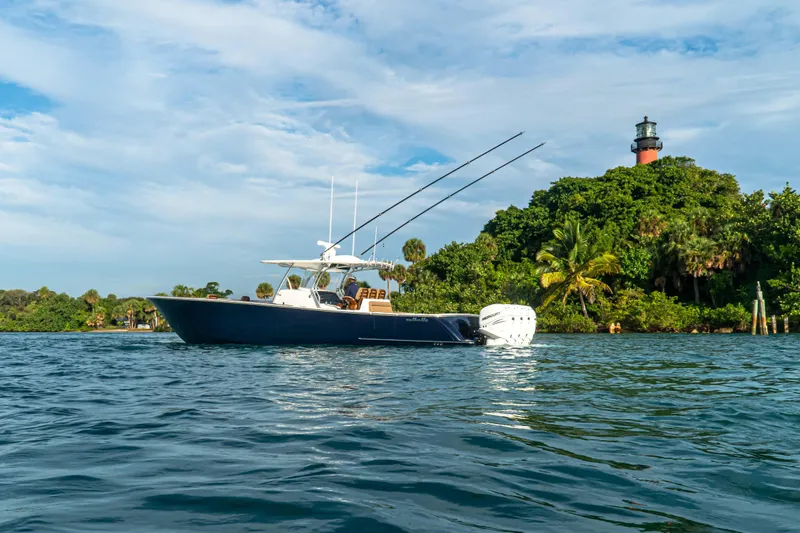 Slide: The Image of 2026 Valhalla Boatworks V-41 cruising near lush island with lighthouse in background. - 2