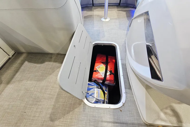 Slide: The Image of Open storage compartment on 2024 Bennington RX 23 RXFBA boat with life jackets inside. - 17