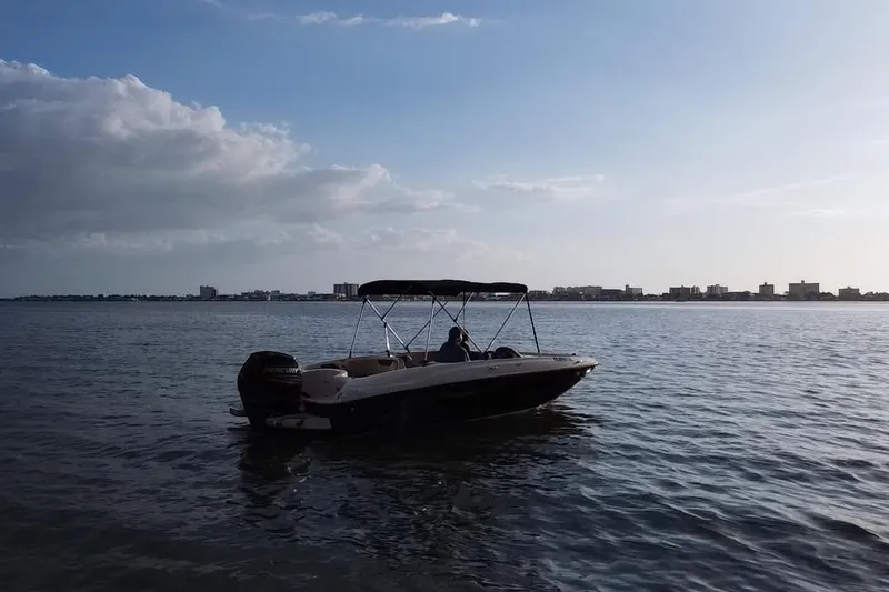 Slide: The Image of 2019 Bayliner Element E18 boat on calm water with city skyline in background. - 19