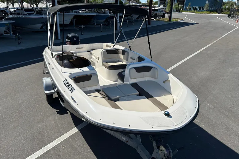 Slide: The Image of 2019 Bayliner Element E18 boat with canopy, parked on a trailer in a marina. - 6