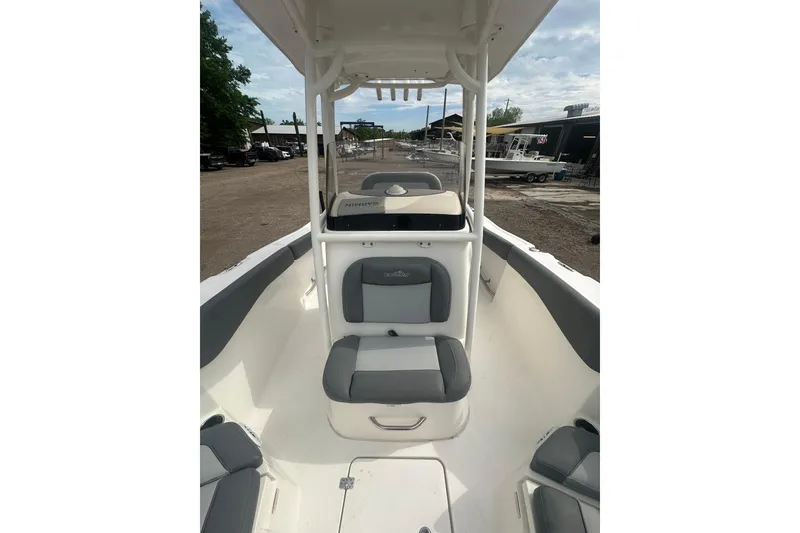 Slide: The Image of 2023 NAUTIC STAR 22 L boat interior with seating and console, parked outdoors. - 33