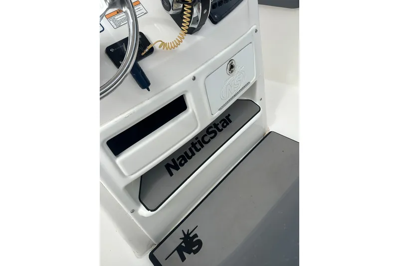 Slide: The Image of 2023 Nautic Star 22 L boat console with steering wheel and storage compartments. - 40
