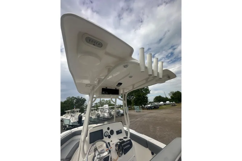 Slide: The Image of 2023 NAUTIC STAR 22 L boat console with T-top and rod holders under cloudy sky. - 43