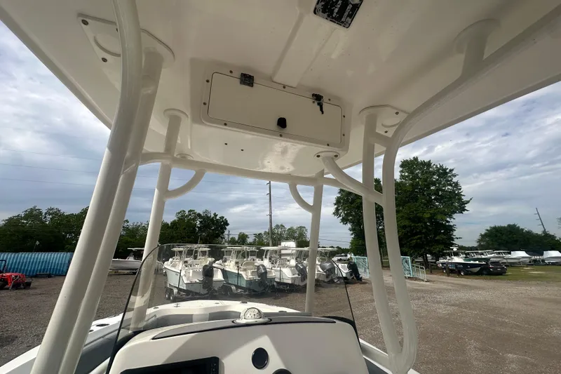 Slide: The Image of 2023 NAUTIC STAR 22 L boat interior with T-top and console, parked outdoors. - 44