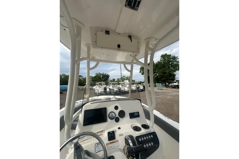 Slide: The Image of 2023 NAUTIC STAR 22 L boat dashboard with steering wheel and controls, parked outdoors. - 45