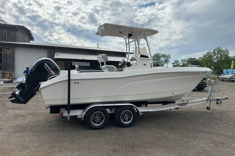 Slide: The Image of 2023 NAUTIC STAR 22 L boat on trailer, parked outdoors under cloudy sky. - 7