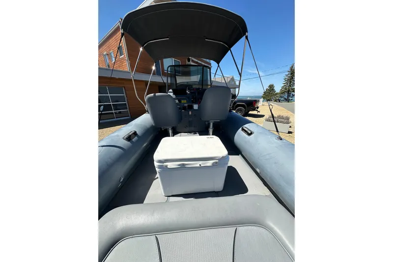 Slide: The Image of 2018 Sealegs 7.7 Amphibious RIB with canopy, parked near modern building. - 18