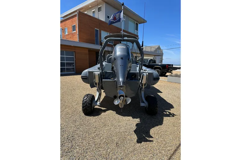 Slide: The Image of 2018 Sealegs 7.7 Amphibious RIB parked on gravel driveway, modern house in background. - 6