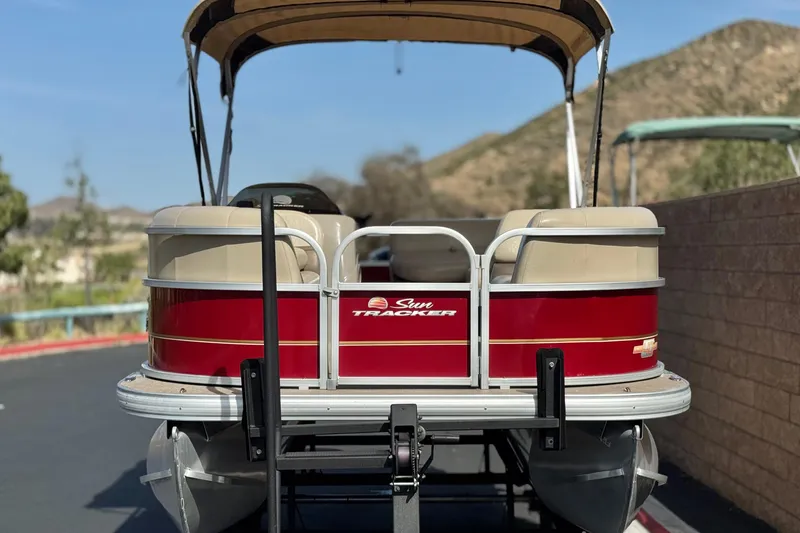 Slide: The Image of 2023 Sun Tracker Party Barge 18 DLX pontoon boat, red and beige, parked outdoors. - 2