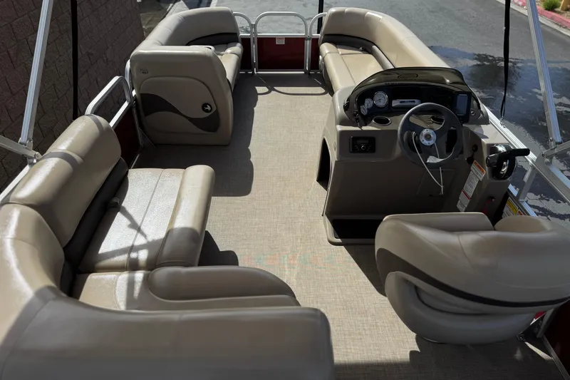 Slide: The Image of 2023 Sun Tracker Party Barge 18 DLX interior with beige seating and steering console. - 20
