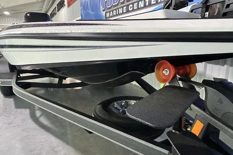 Slide: The Image of 2026 Skeeter ZX150 boat on trailer, showcasing hull and roller details in a showroom. - 5