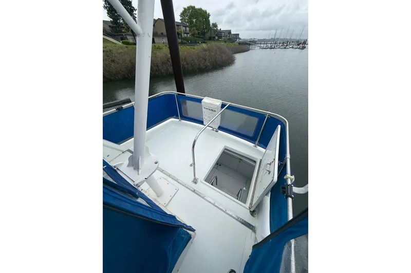 Slide: The Image of 1979 Uniflite 37 Coastal Cruiser deck view with blue trim, docked by a marina. - 11