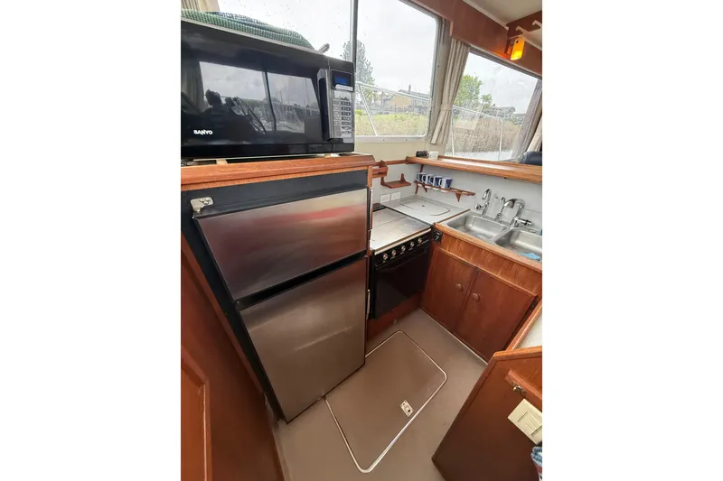 Slide: The Image of 1979 Uniflite 37 Coastal Cruiser kitchen with microwave, fridge, stove, and double sink. - 23