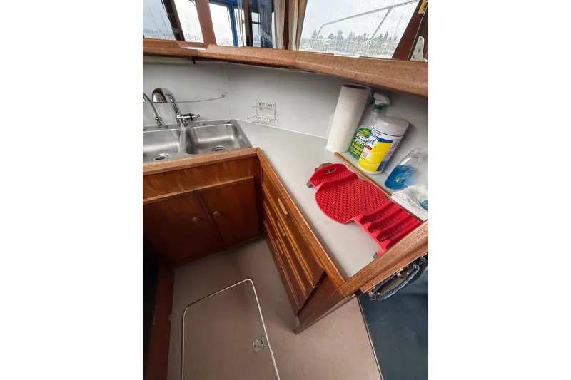 Slide: The Image of 1979 Uniflite 37 Coastal Cruiser kitchen with dual sinks and cleaning supplies. - 24