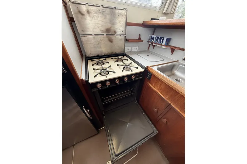 Slide: The Image of 1979 Uniflite 37 Coastal Cruiser kitchen with stove, oven, sink, and wooden cabinetry. - 25