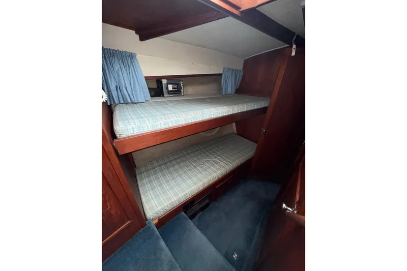 Slide: The Image of 1979 Uniflite 37 Coastal Cruiser cabin with bunk beds and blue curtains. - 26