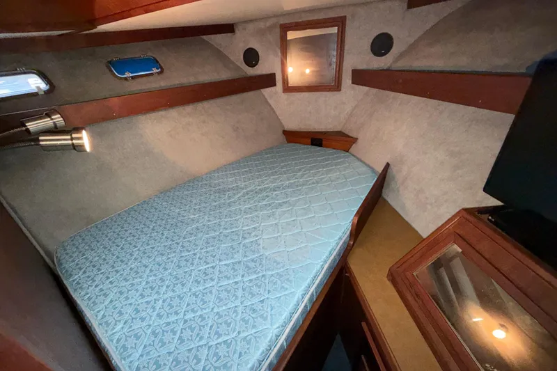 Slide: The Image of 1979 Uniflite 37 Coastal Cruiser cabin with bed, wood accents, and porthole windows. - 27
