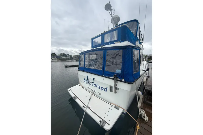 Slide: The Image of 1979 Uniflite 37 Coastal Cruiser docked, featuring blue canopy and Portland, OR markings. - 3