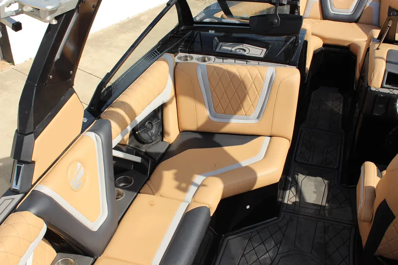 Slide: The Image of 2022 Tigé 23ZX boat interior with tan and black seating, featuring cup holders and stylish design. - 10