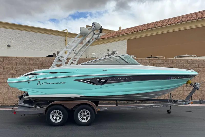 The Image of 2022 Crownline 220 SS SURF boat on trailer, turquoise color, parked outdoors. - 0