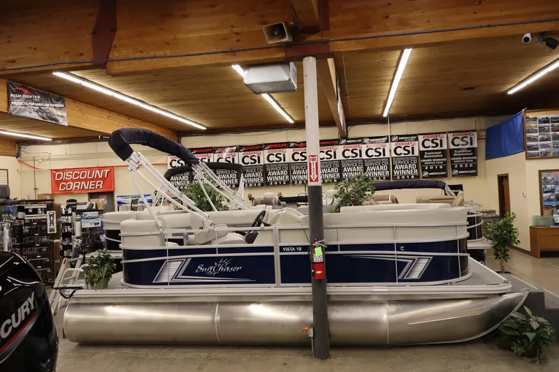 The Image of 2025 SunChaser Vista 18 Fish pontoon boat displayed indoors with award banners. - 1