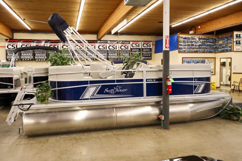 Slide: The Image of 2025 SunChaser Vista 18 Fish pontoon boat displayed indoors with award banners. - 3