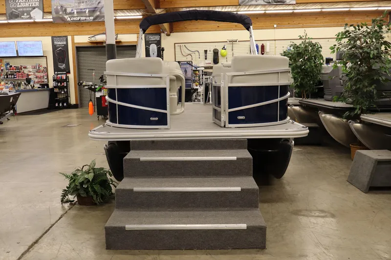 Slide: The Image of 2025 SunChaser Vista 18 Fish pontoon boat displayed indoors with steps and plants. - 4