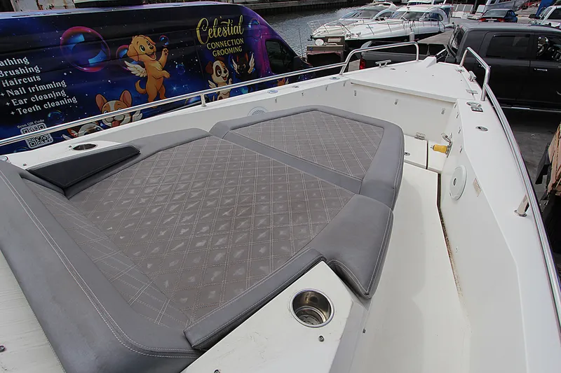 Slide: The Image of 2018 Axopar 37 Sun-Top boat with cushioned seating and marina background. - 13