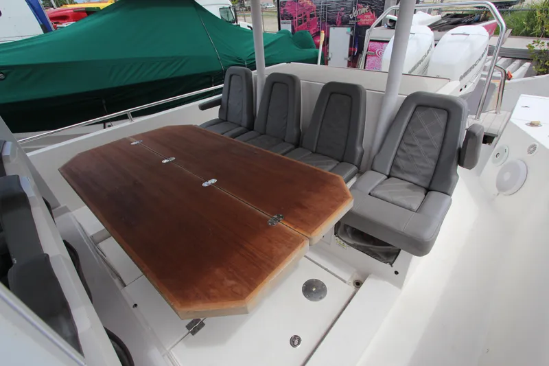 Slide: The Image of 2018 Axopar 37 Sun-Top boat interior with wooden table and cushioned seating. - 6