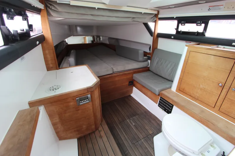 Slide: The Image of 2018 Axopar 37 Sun-Top cabin interior with wood finish and seating area. - 9