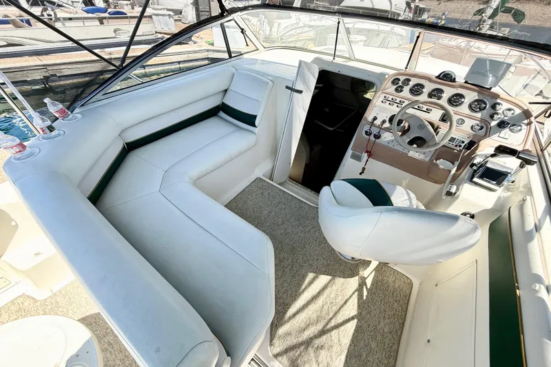 Slide: The Image of 1998 Rinker Fiesta Vee 280 boat interior with white seating and table, docked by the water. - 7