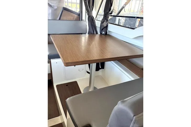 Slide: The Image of Interior of 2023 Beneteau Antares 7, featuring a wooden table and cushioned seating. - 16