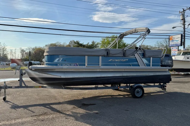 Slide: The Image of 2018 Starcraft EX 22 C SG pontoon boat on trailer, parked outdoors. - 2