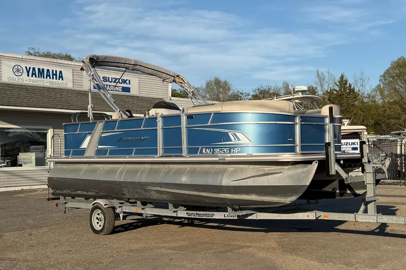 Slide: The Image of 2018 Starcraft EX 22 C SG pontoon boat on trailer, parked outside Yamaha dealership. - 4